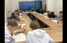 Uczestnicy konkursu siedzą w ławkach i rozwiązują test