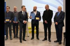 Laureaci konkursu Okręgowego Inspektoratu Pracy. Przedstawiciele pracodawców stoją na scenie, w dłoniach trzymają otrzymane grawertony.