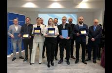 Laureaci konkursu Okręgowego Inspektoratu Pracy. Przedstawiciele pracodawców stoją na scenie, w dłoniach trzymają otrzymane grawertony.