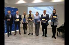 Laureaci konkursu Okręgowego Inspektoratu Pracy. Przedstawiciele pracodawców stoją na scenie, w dłoniach trzymają otrzymane grawertony.