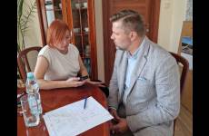 Elżbieta Samsel-Czerniawska, dziennikarka i Paweł Graczyk, Z-ca OIP siedzą przy stole. Dziennikarka trzyma w ręku dyktafon. P. Graczyk udziela dziennikarce informacji, przed nim na stole leżą kartki z notatkami.