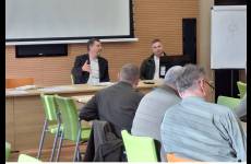 Widok na salę szkoleniową. Uczestnicy spotkania siedzą przy stołach