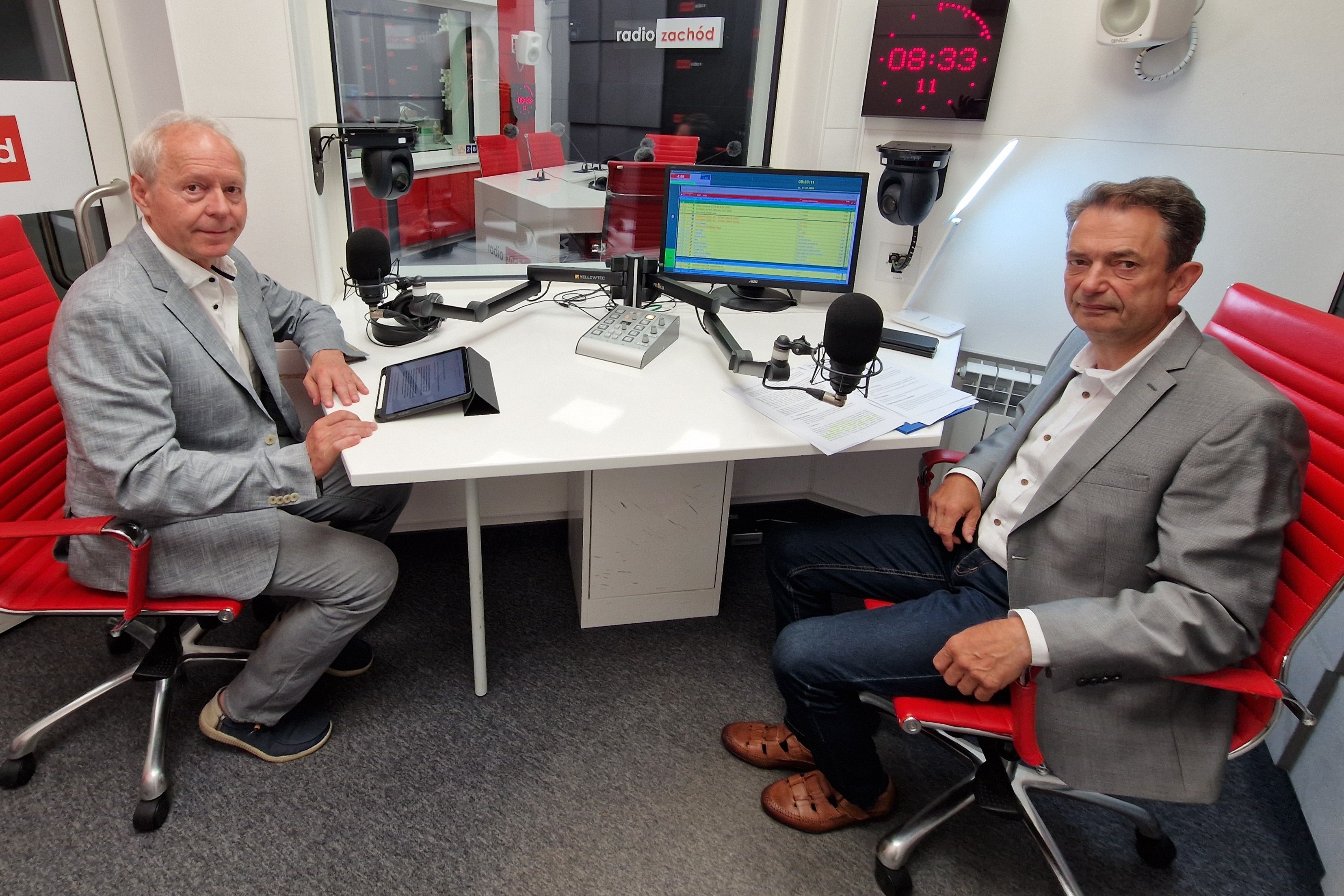 Redaktor Krzysztof Baług i Jerzy Łaboński OIP siedzą przy konsoli w studiu radiowym